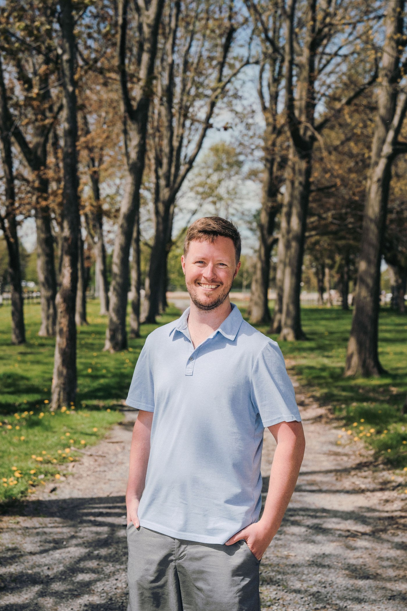 Stephen Cuthbertson standing outdoors on a tree-lined path, smiling